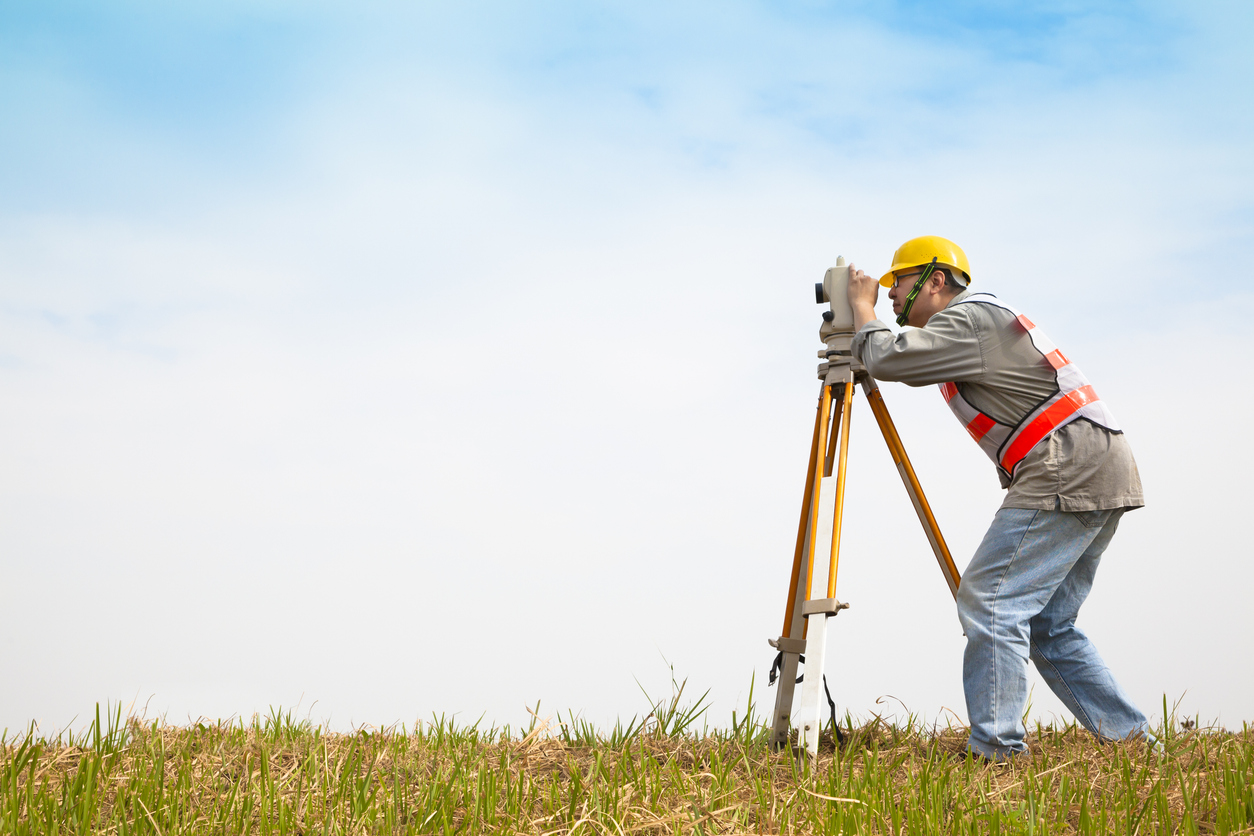 Professional Surveyor taking measurements of field 